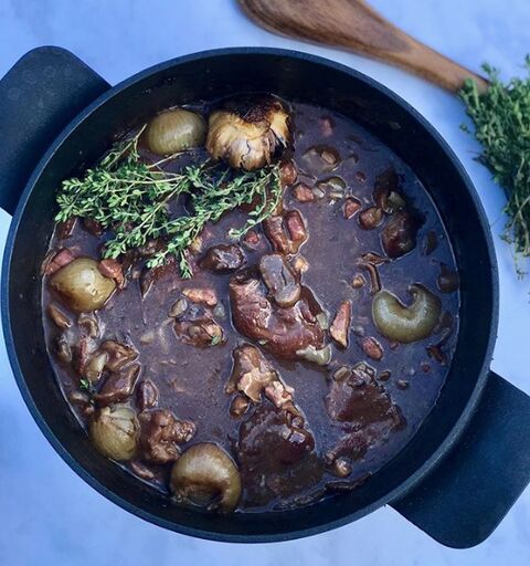 Mandy's boeuf bourguignon in a black casserole, with baby onions, mushrooms and fresh thyme